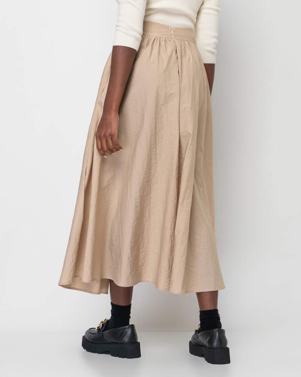 Μακριά μπεζ φαρδιά φούστα με λάστιχο στη μέση. Εμφάνιση από πίσω