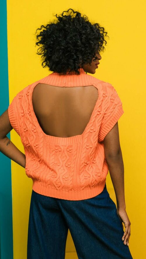Πλεκτή αμάνικη πορτοκαλί ζακέτα με V λαιμόκοψη, άνοιγμα στην πλάτη και μπροστά κουμπιά. Εμφάνιση από πίσω