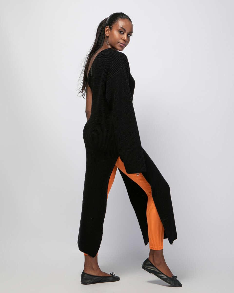 Μακριά μαύρη πλεκτή μπλούζα με έναν ώμο, φαρδύ μανίκι και ανοίγματα στα πλαϊνά. Εμφάνιση στο πλάι