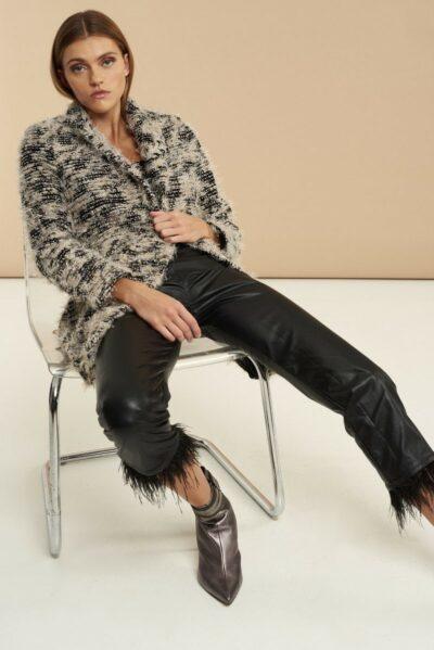 Βραδινό παλτό με ξέφτια, κουμπιά, κλασικό γιακά και εξωτερικές τσέπες. Εμφάνιση καθιστή σε καρέκλα.