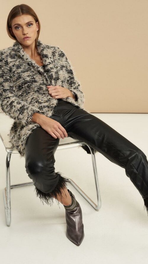 Βραδινό παλτό με ξέφτια, κουμπιά, κλασικό γιακά και εξωτερικές τσέπες. Εμφάνιση καθιστή σε καρέκλα.