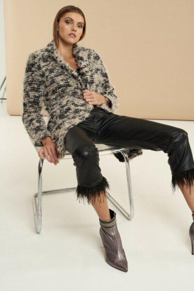 Βραδινό παλτό με ξέφτια, κουμπιά, κλασικό γιακά και εξωτερικές τσέπες. Εμφάνιση καθιστή σε καρέκλα.